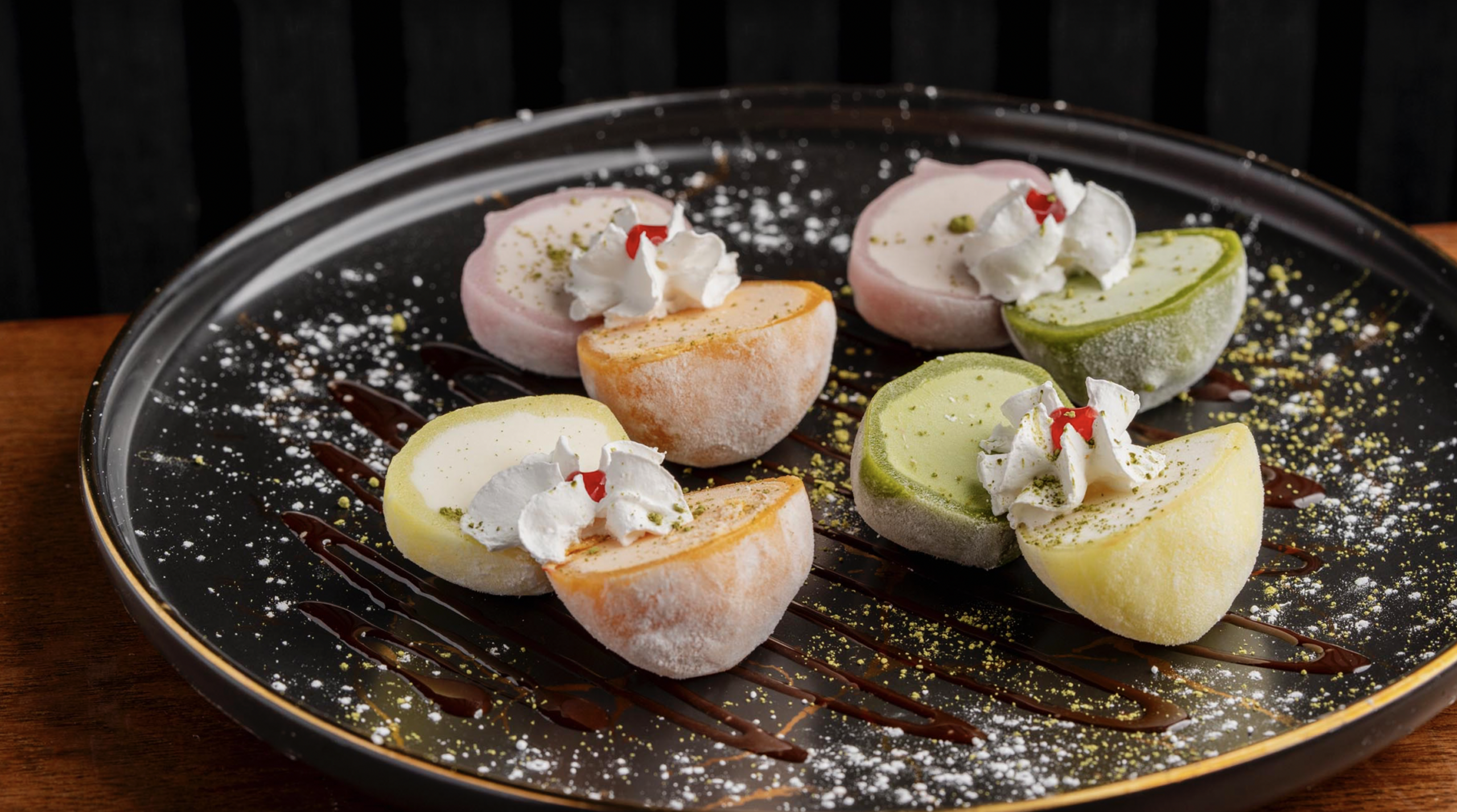 Halved mochi ice cream in assorted flavors topped with whipped cream and cherries